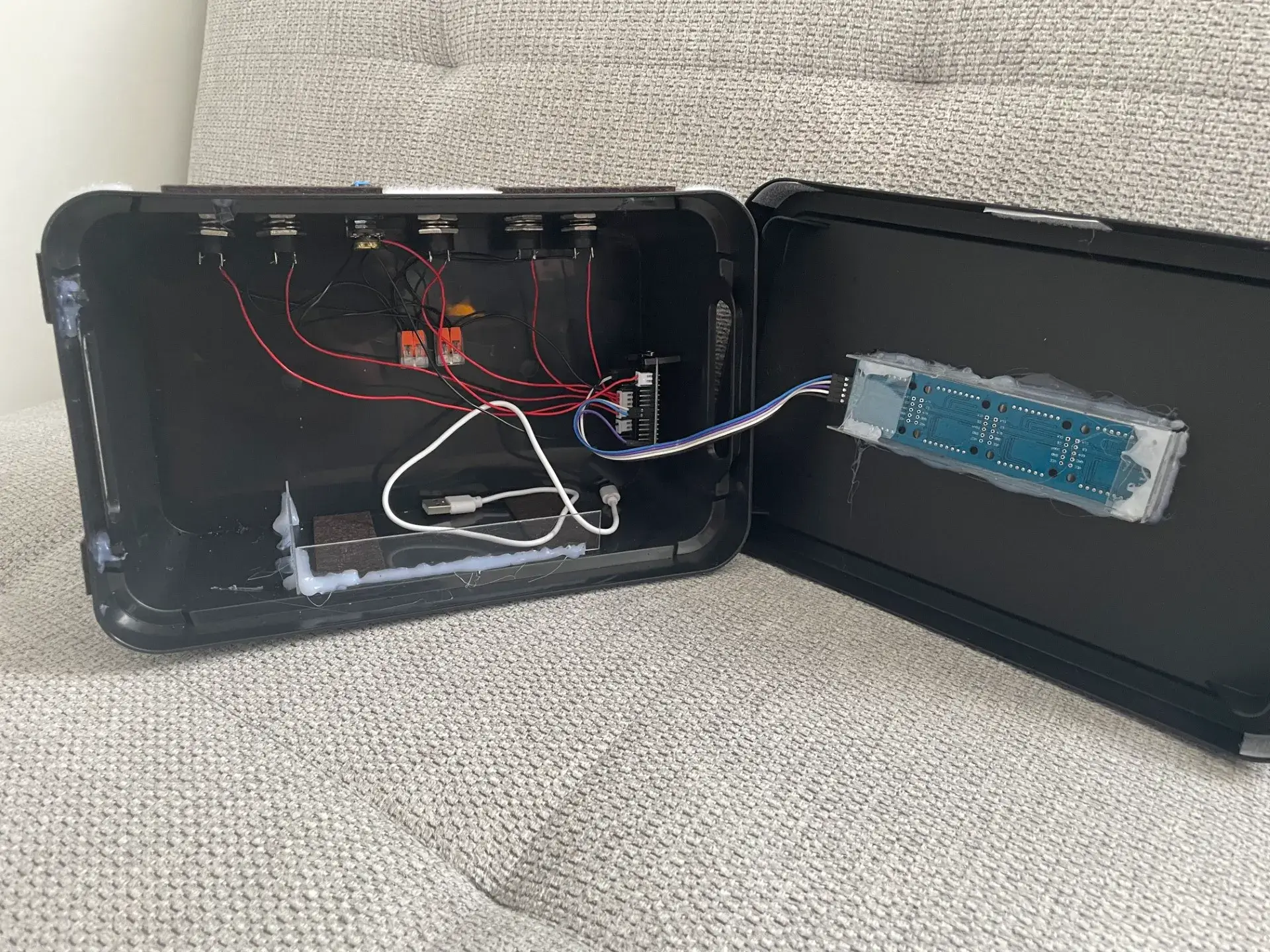 Geöffnete Box: links die Verkabelung von Tastern und ESP32, rechts der Deckel mit der eingeklebten LED-Matrix, verbunden über ein Flachkabel
